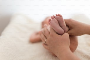 Una madre tiene i piedi nudi di un neonato. Piedi minuscoli nella mano della donna, primo piano