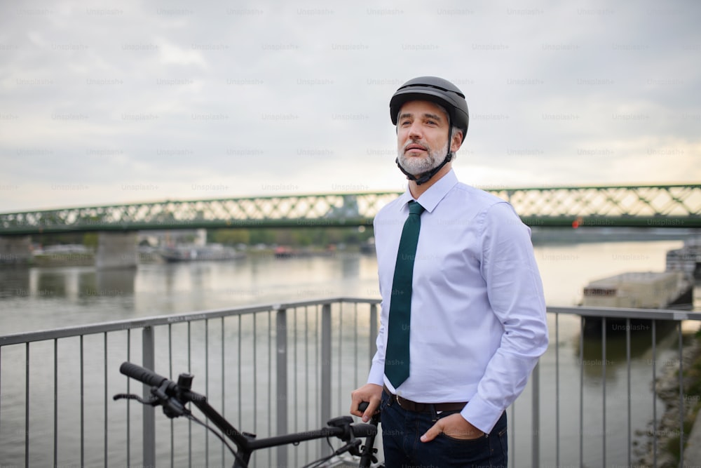 通勤途中のビジネスマン通勤者、橋の上に立って自転車で走る、持続可能なライフスタイルのコンセプト。