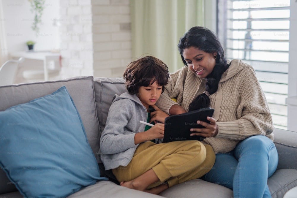 An Indian mother using tablet with her little son and having fun at home.