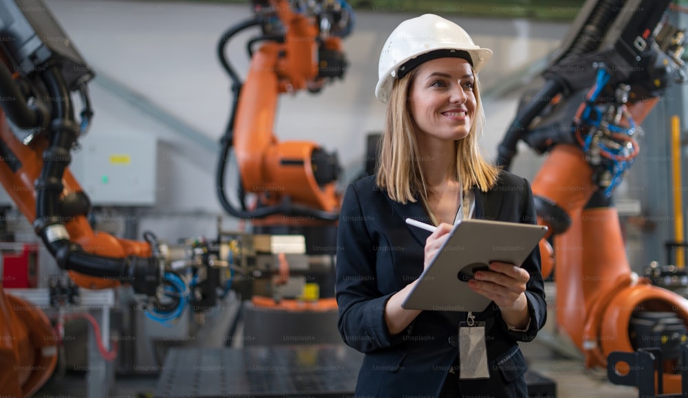 A female chief engineer in modern industrial factory using tablet and making audit.