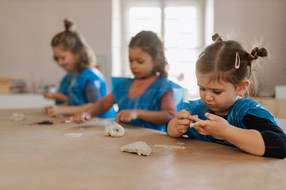 A group of little kids working with pottery clay during creative art and craft class at school.