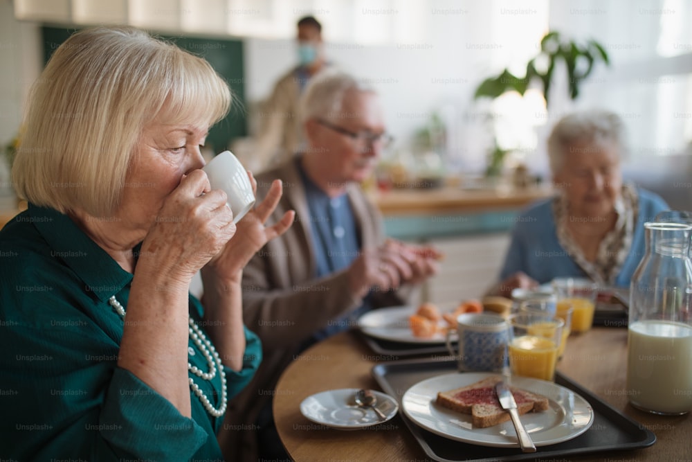 요양원 케어 센터에서 아침 식사를 즐기는 쾌활한 노인 그룹.
