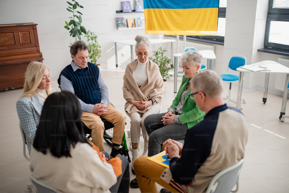 Un groupe de personnes âgées priant ensemble pour l’Ukraine dans le centre communautaire de l’église.
