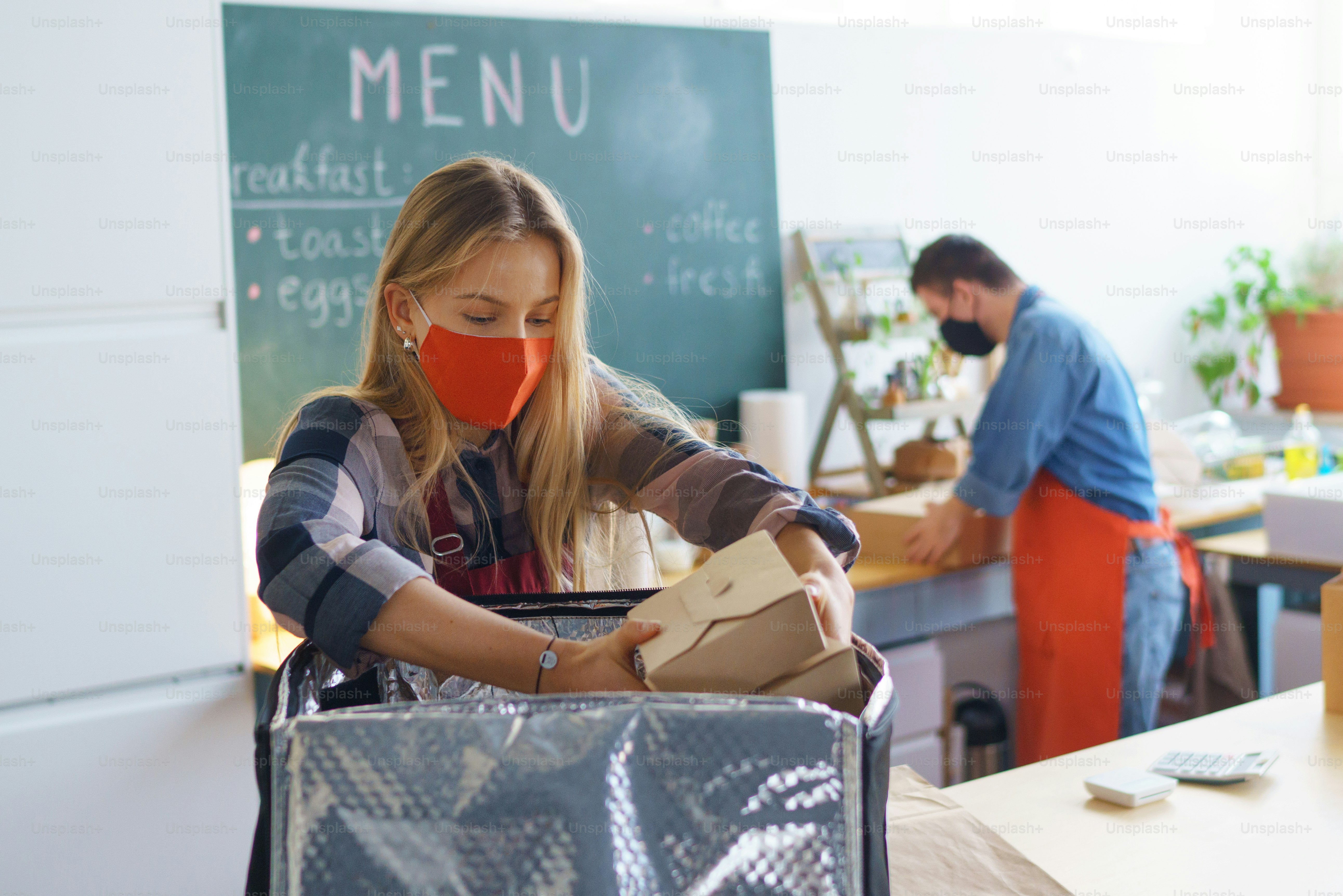 Un joven camarero con síndrome de Down que trabaja con un colega en un restaurante de comida para llevar, concepto de inclusión social.