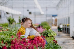 Une fleuriste étreignant sa jeune collègue trisomique dans une jardinerie.
