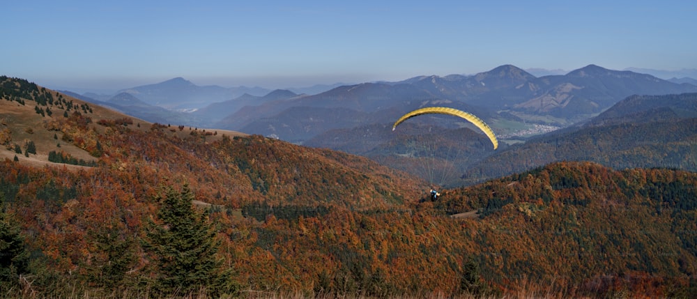 Un parapente volant dans le ciel bleu avec la montagne en arrière-plan.