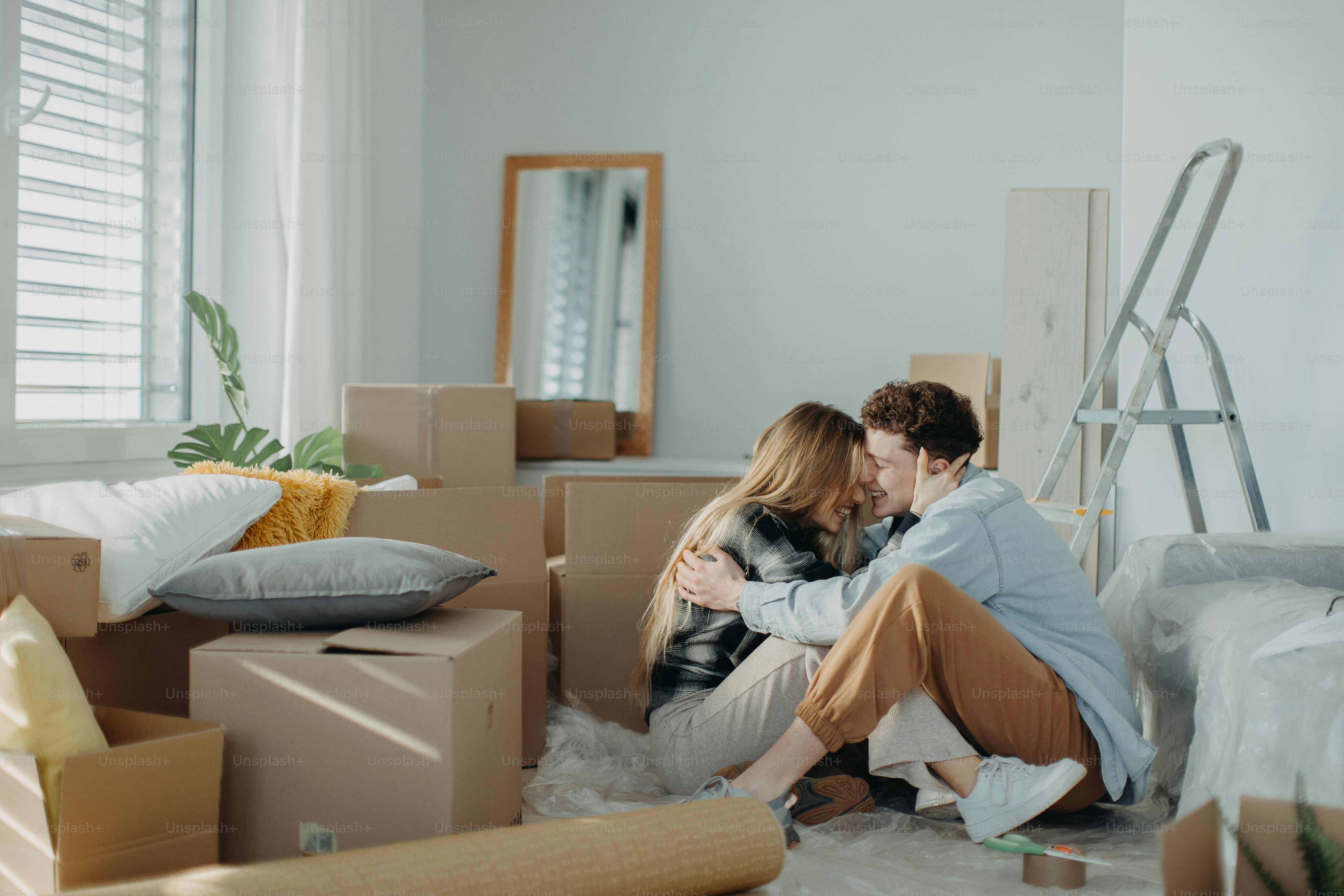 A cheerful young couple in their new apartment, carrying carpet ...