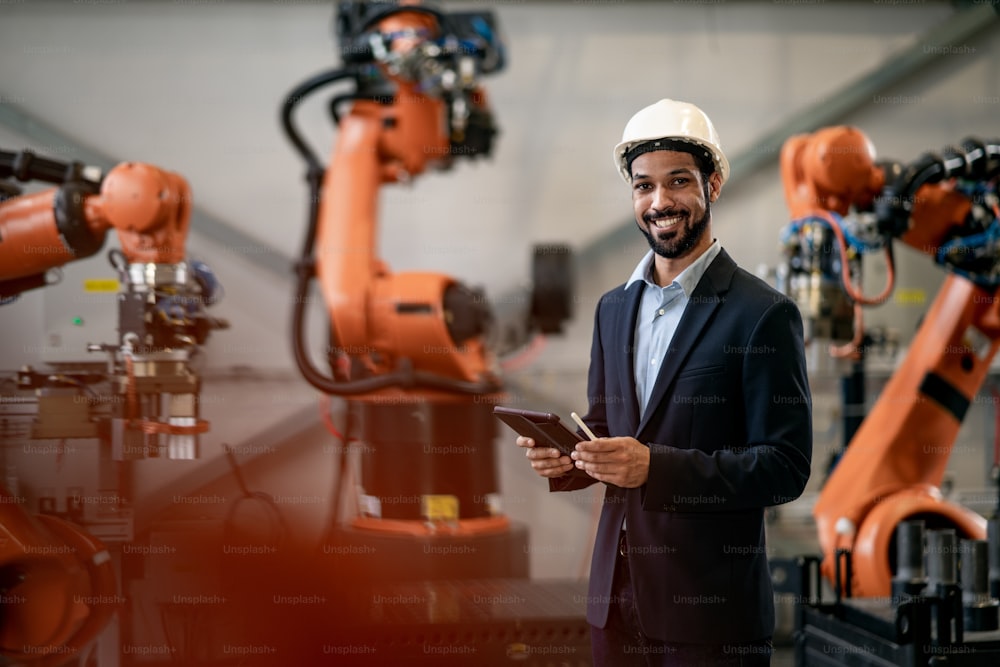 Ein Automatisierungsingenieur verwendet ein Tablet für die Programmierung des Roboterarms in der Fabrik.