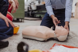 A close-up of male instructor showing first medical aid on doll during training course indoors