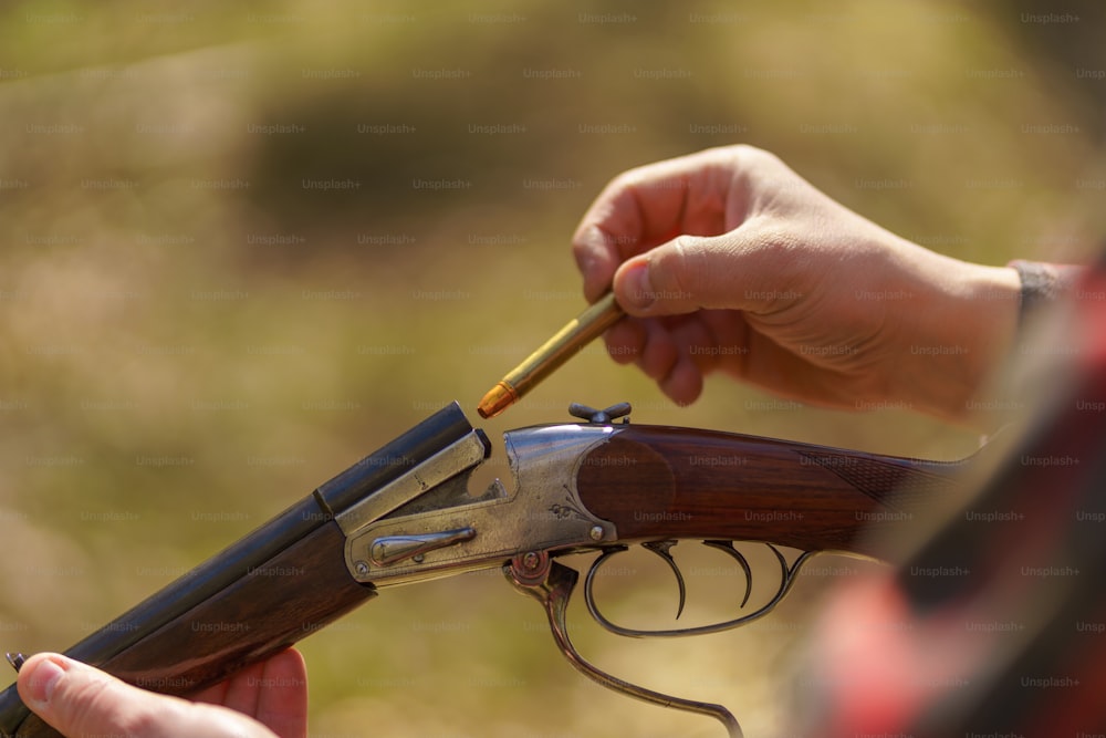사냥꾼의 클로즈업이 숲에서 소총 총에 카트리지를 충전합니다.
