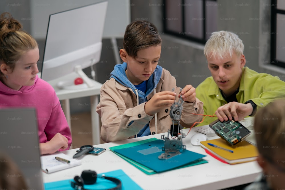 Un grupo de niños felices con su profesor de ciencias con juguetes eléctricos y robots en el aula de robótica
