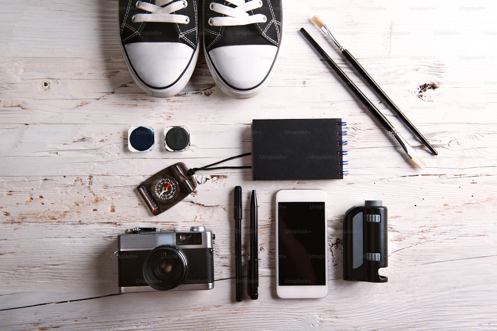 Desk with smartphone and school supplies. Studio shot on white wooden background.