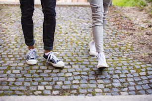 見分けのつかない若い観光客2人の足。旧市街を歩く10代の少女と少年。