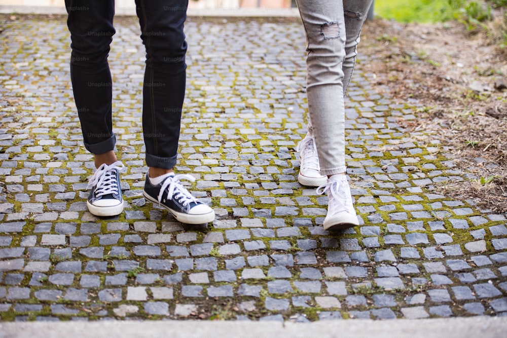 Gambe di due giovani turisti irriconoscibili. Ragazza e ragazzo adolescenti che camminano nella città vecchia.