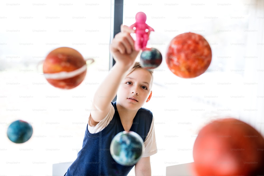 A small boy with model of solar system indoors, playing.