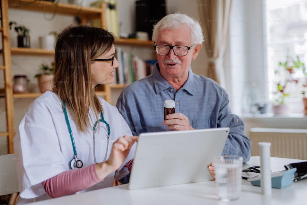 Un operatore sanitario o un caregiver che visita un uomo anziano in casa a casa, spiegando il dosaggio del farmaco.