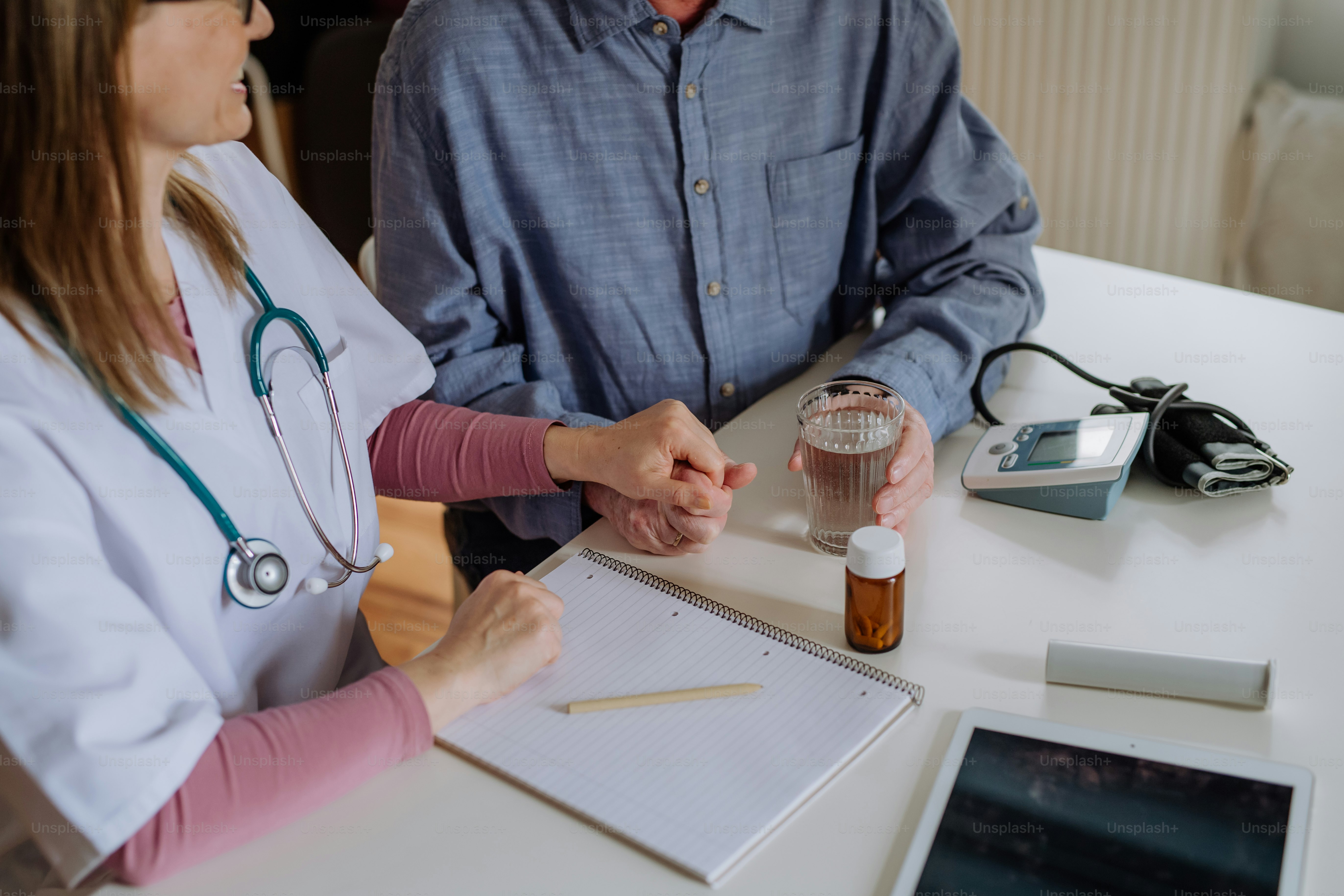 A close-up of doctor holding hand of senior patient and consoling him ...