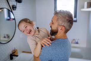 A happy father hugging his little daughter in bathroom.