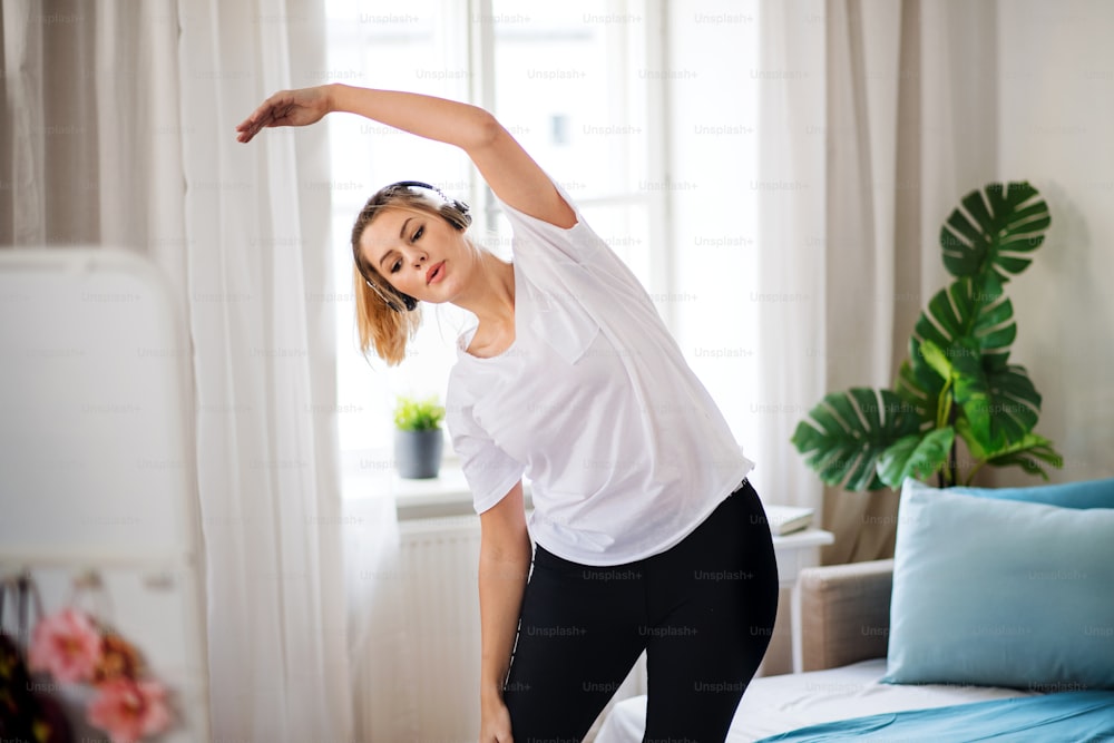 A young woman doing exercise in bedroom indoors at home.