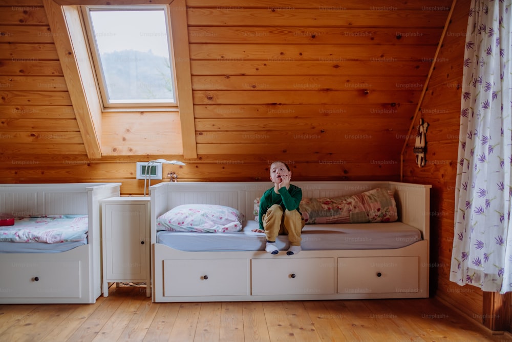 Un petit garçon atteint du syndrome de Down assis sur son lit à la maison.