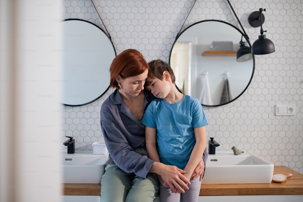 Una madre abrazando y consolando a un niño pequeño en el baño de su casa.