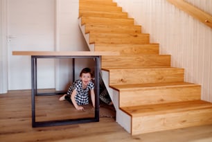 Children playing at home, hiding under stairs. Copy space.
