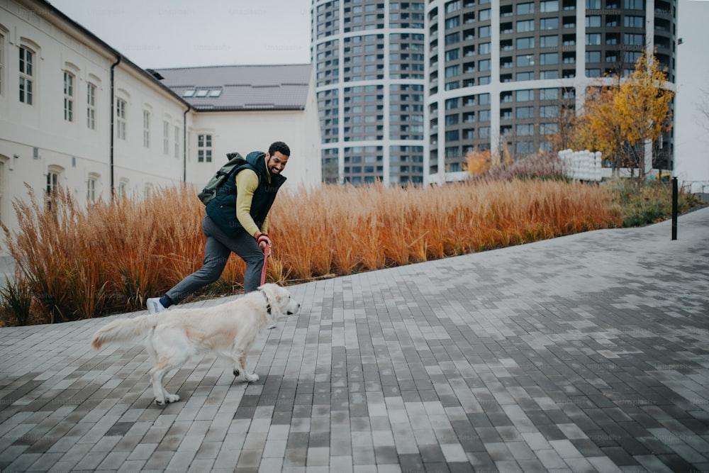 Una vista de ángulo alto de un joven feliz corriendo escaleras arriba con su perro al aire libre en la ciudad.