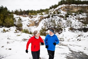 Senior couple jogging outside in winter nature.