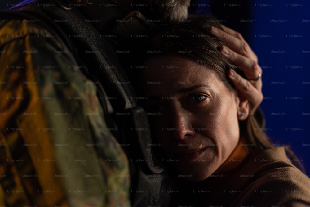 Um close-up de mulher triste chorando ao abraçar seu marido militar e dizer adeus a ele.