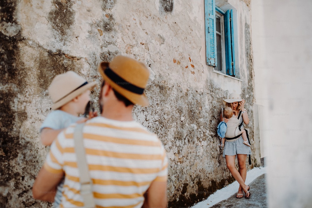 Una familia joven con dos niños pequeños y sombreros en la ciudad de vacaciones de verano.