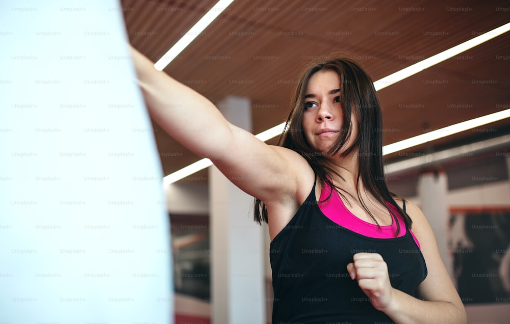 Eine attraktive junge Frau, die drinnen im Fitnessstudio Karate übt. Speicherplatz kopieren.