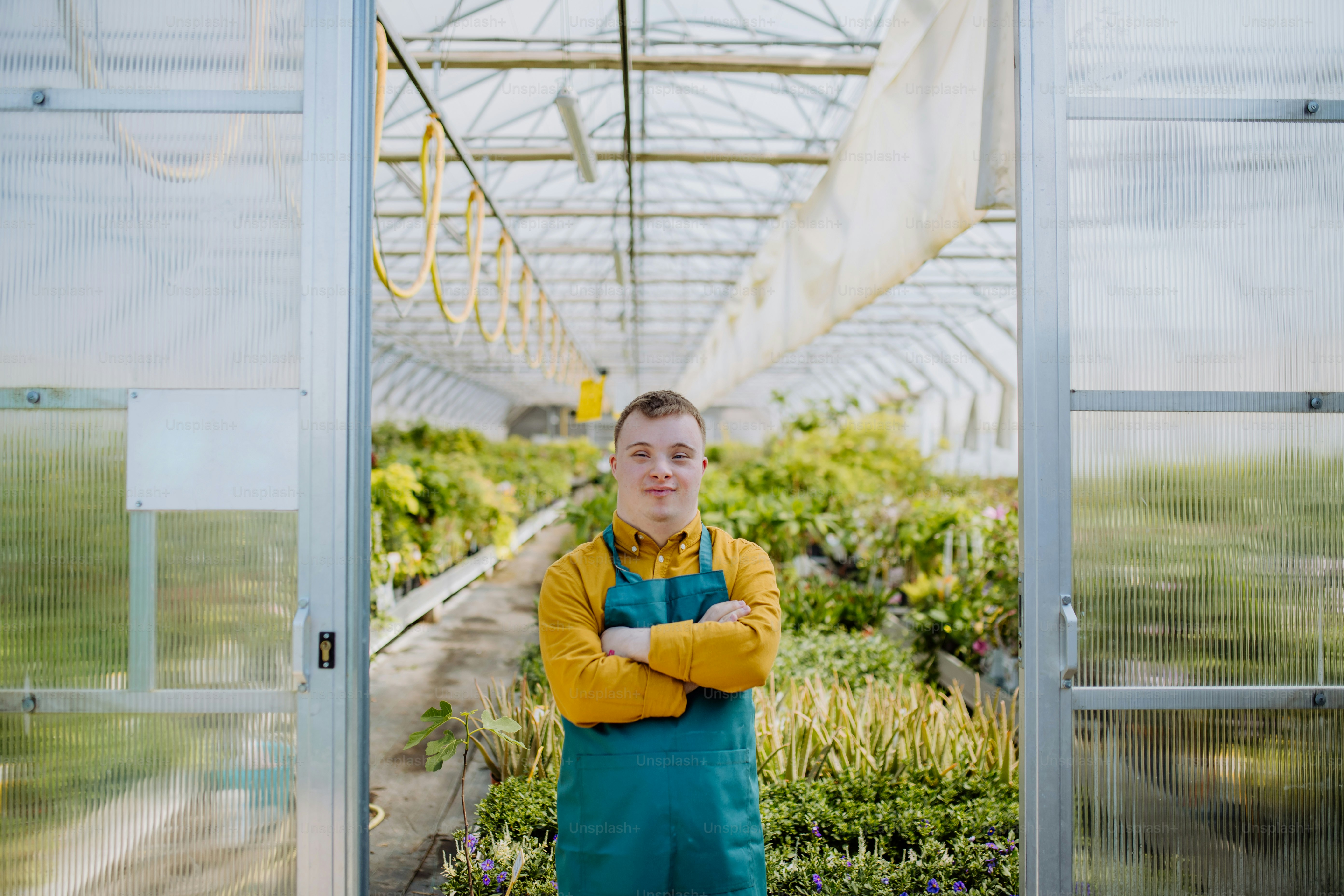 A young employee with Down syndrome working in garden centre, looking at camera