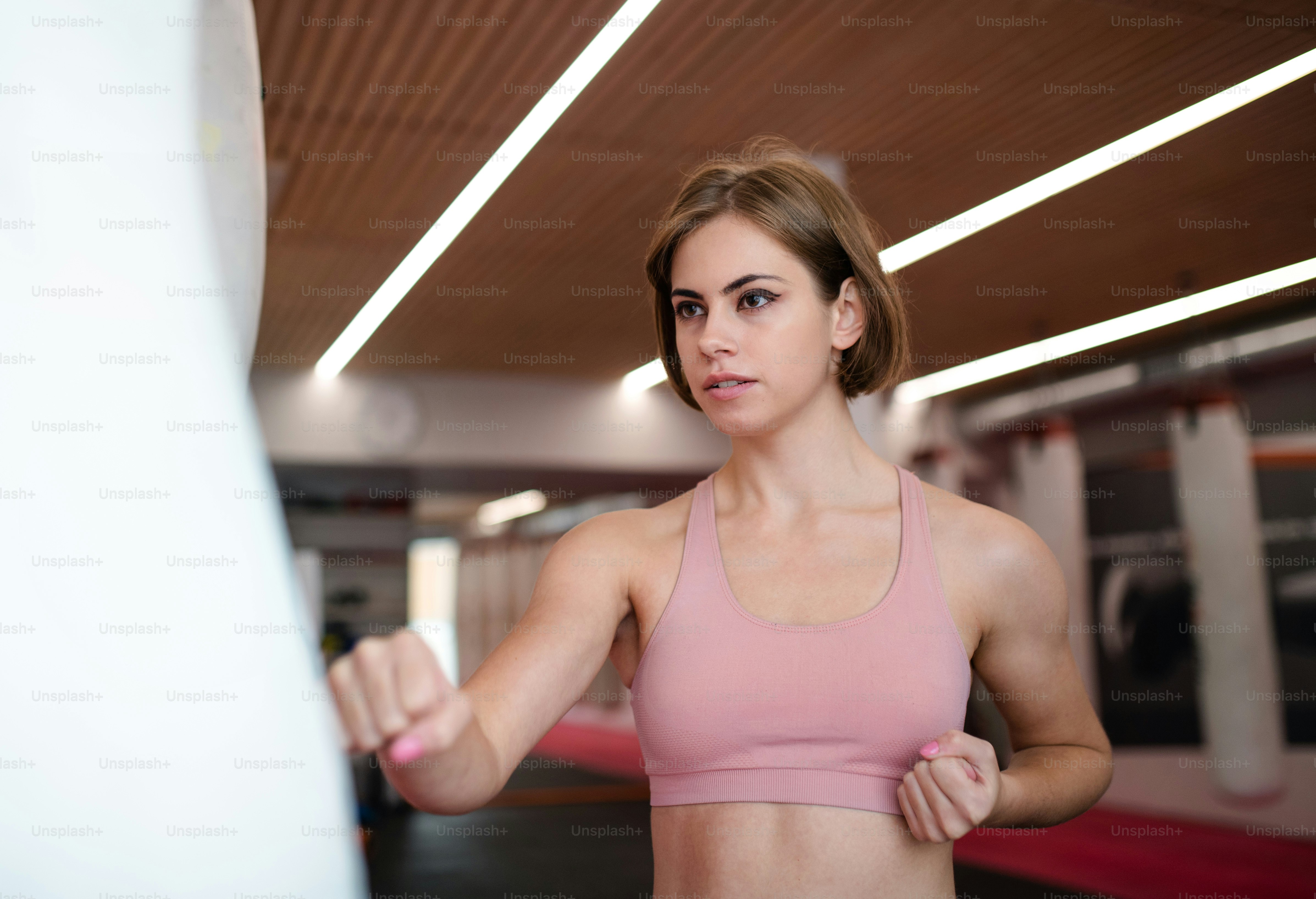 Seorang wanita muda yang menarik berlatih karate di dalam ruangan di gym. Salin ruang.