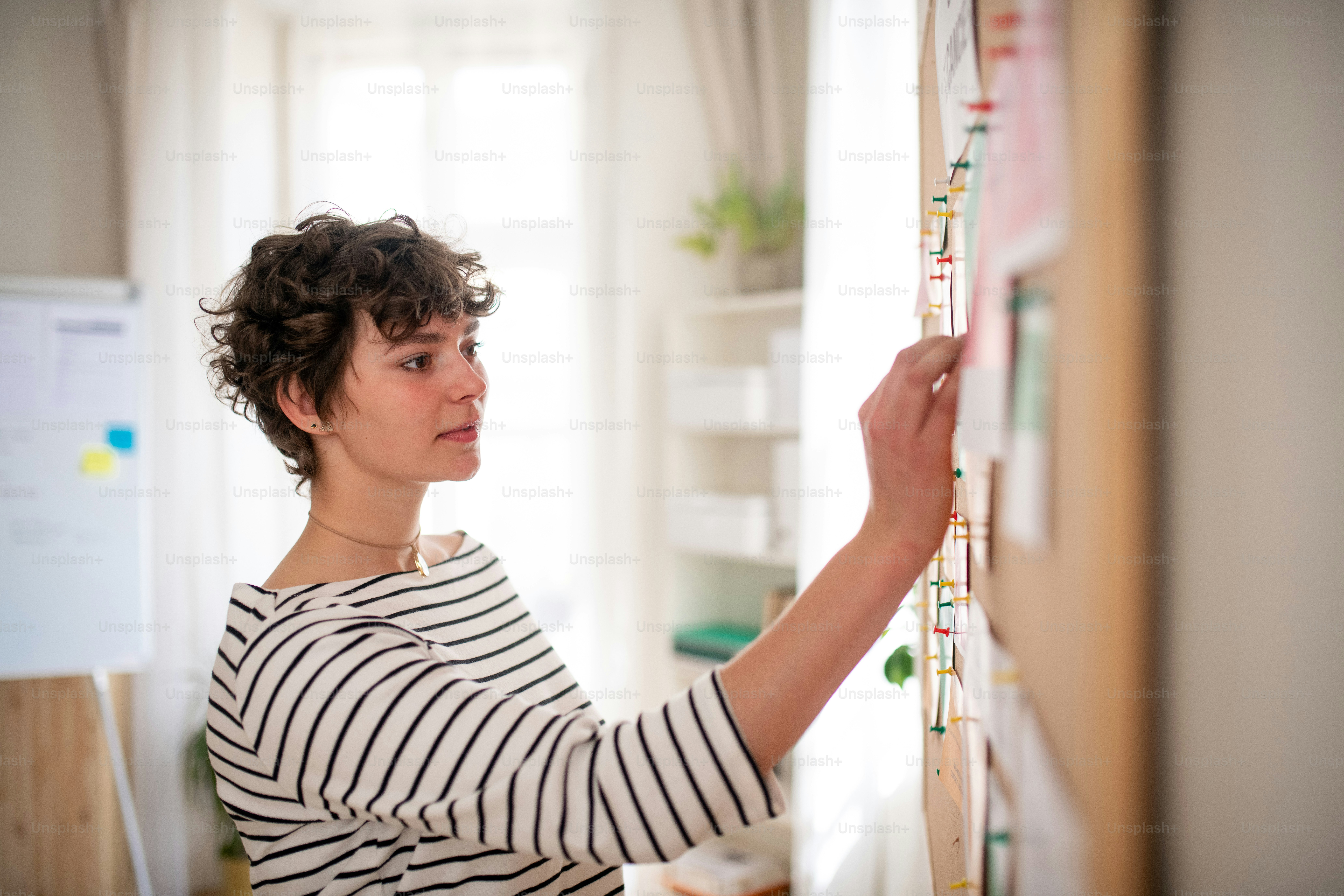 A job center employee pinning job vacancies on employment noticeboard.