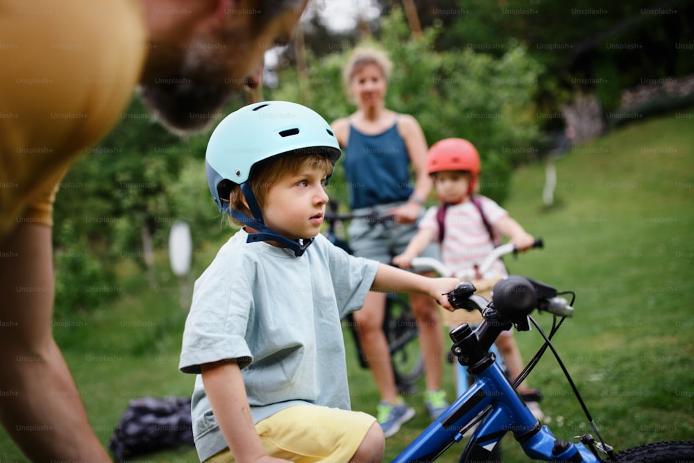 A young family with little children preaparing for bike ride, in front of house.