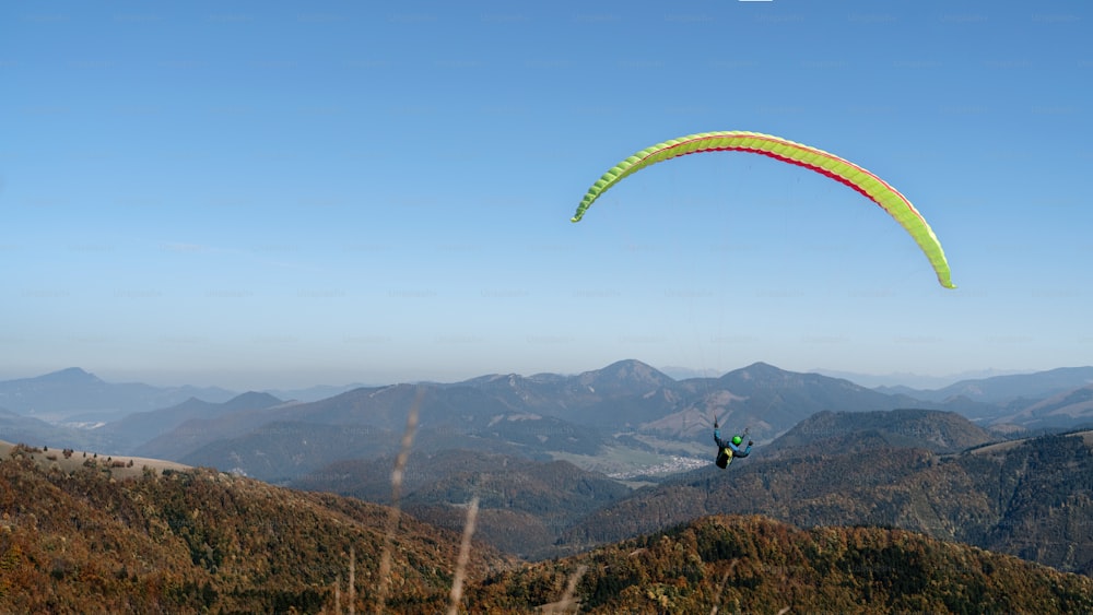 Paragliders flying in a blue sky with mountain in background.