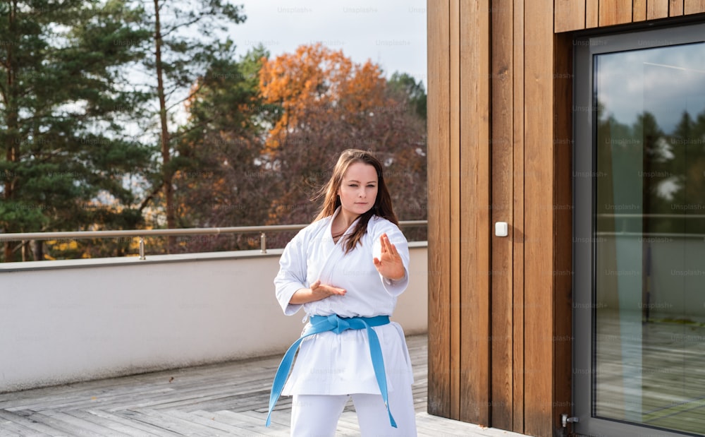 Eine attraktive junge Frau, die im Freien auf der Terrasse Karate übt.