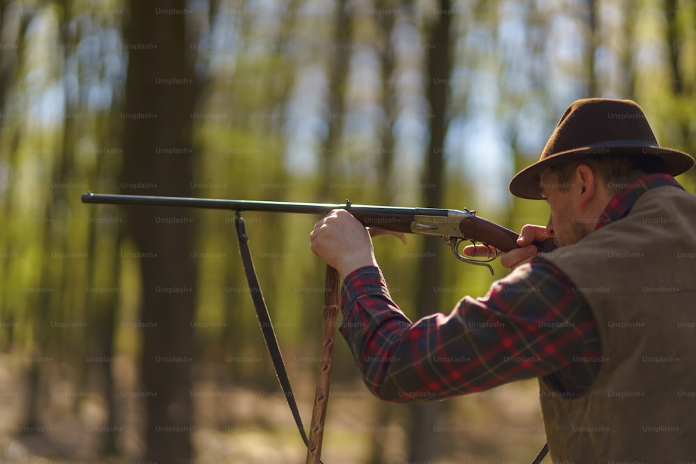 Ein Jäger zielt mit Gewehrgewehr auf Beute im Wald.