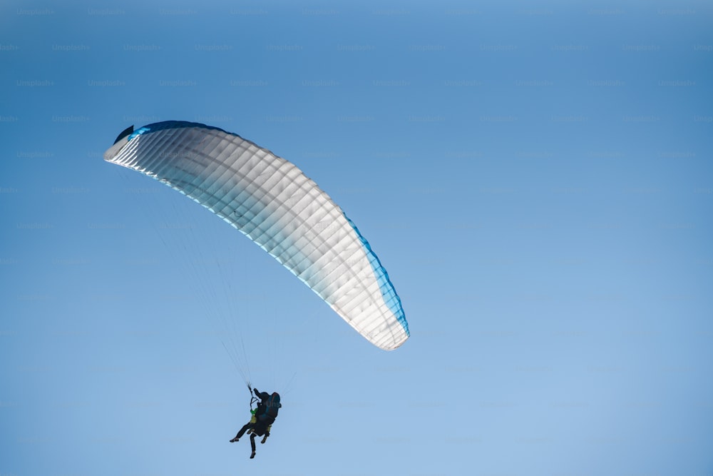 A paraglider in the blue sky. The sportsman flying on a paraglider.