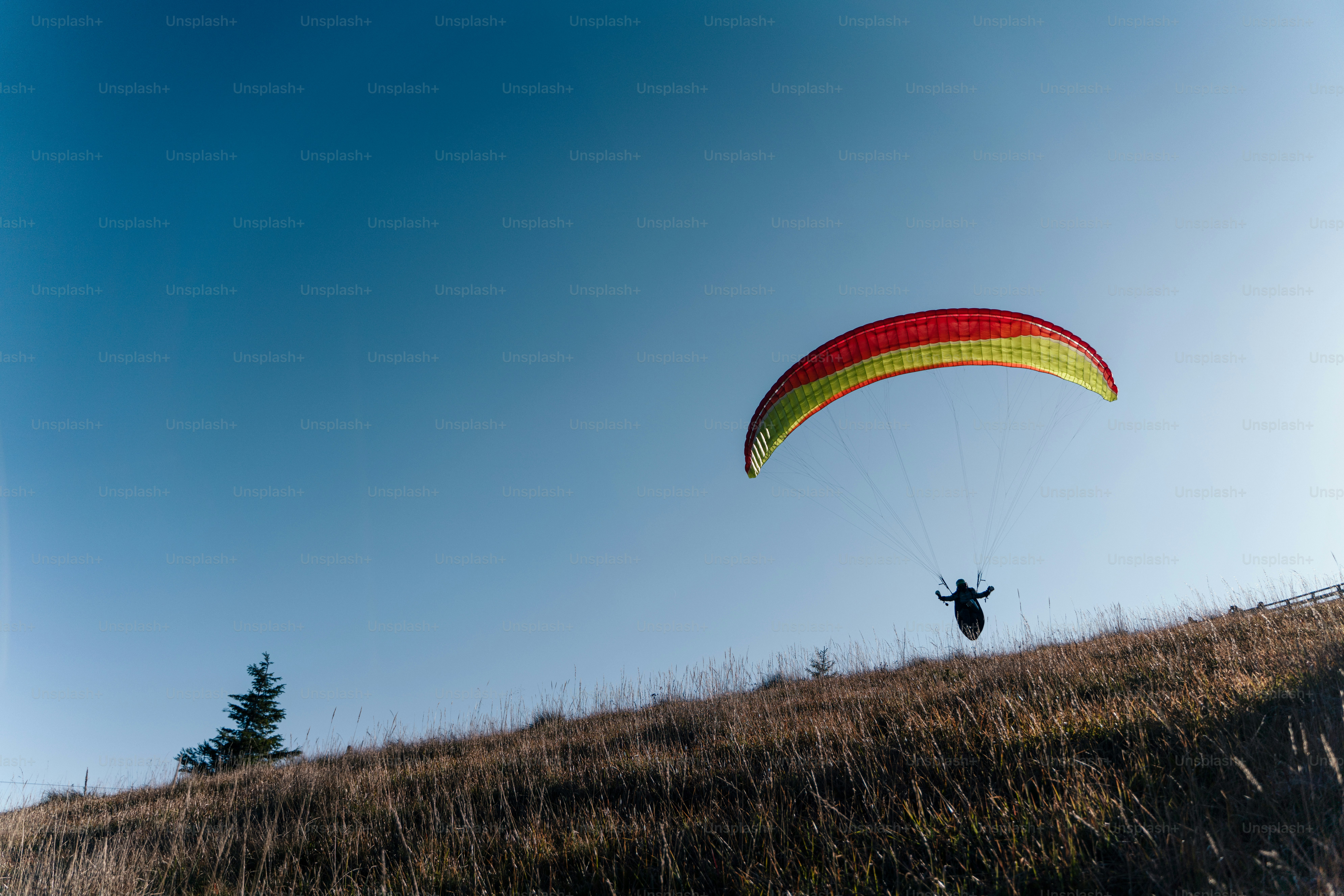 Gleitschirmflieger fliegen in einem blauen Himmel mit Berg im Hintergrund.