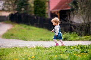 Vista laterale della bambina che cammina in campagna in primavera. Copia spazio.