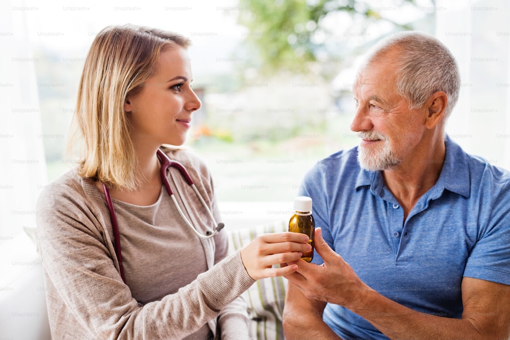 Visitante de saúde e um homem idoso durante a visita domiciliar. Uma enfermeira ou um médico dando remédio a um homem.