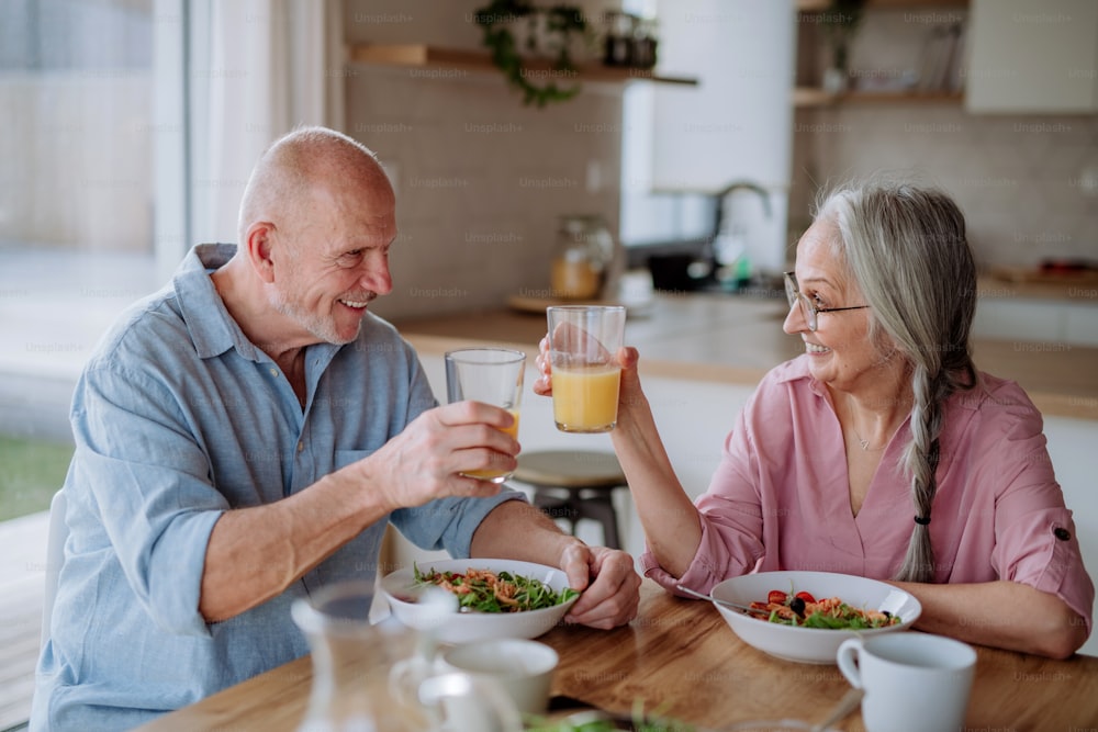 Um casal de idosos felizes jantando juntos em casa.