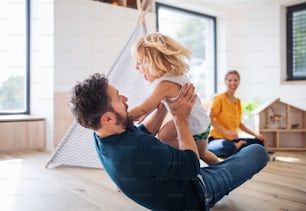 A young family with small child indoors in bedroom having fun.