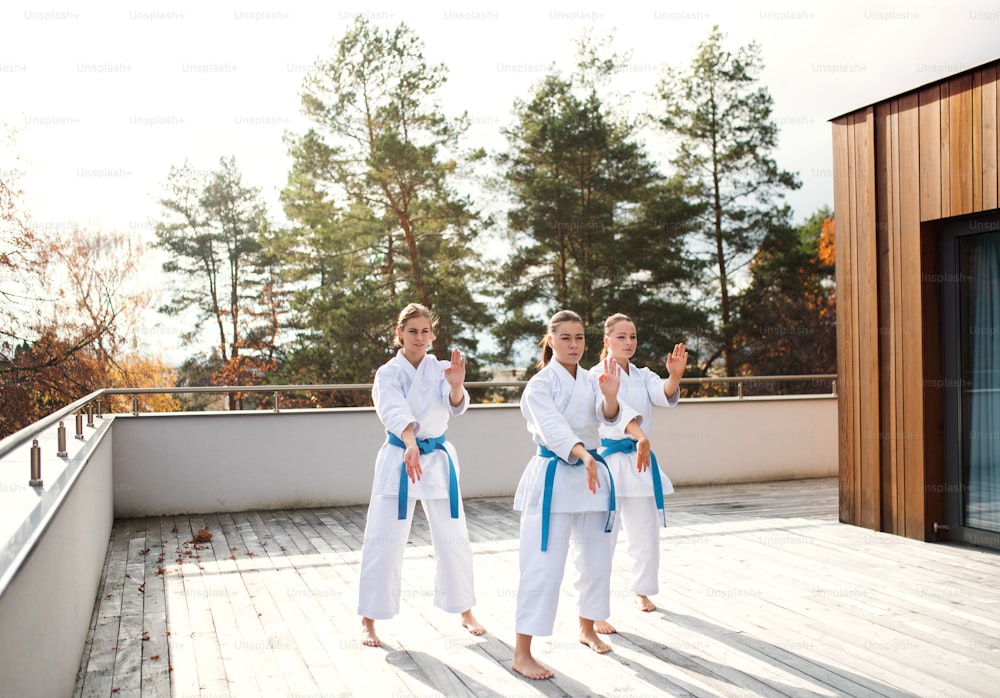 Un grupo de mujeres jóvenes practicando karate al aire libre en una terraza.