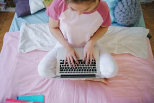 Vista superior de una joven irreconocible con una computadora portátil en la cama, trabajando durante la cuarentena.