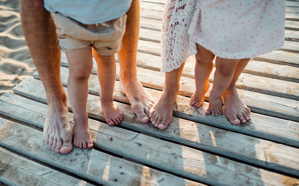 夏休みの浜辺に立つ家族の足と足、中盤とクローズアップ。