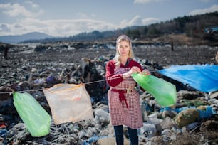 Fashionable modern woman on landfill, consumerism versus plastic pollution concept.