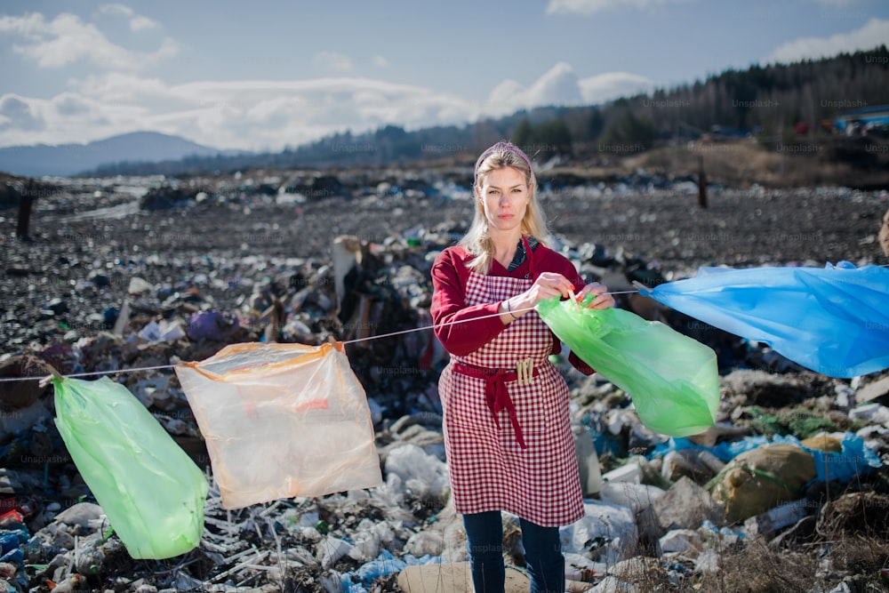 Modische moderne Frau auf Mülldeponie, Konsum versus Plastikverschmutzung Konzept.