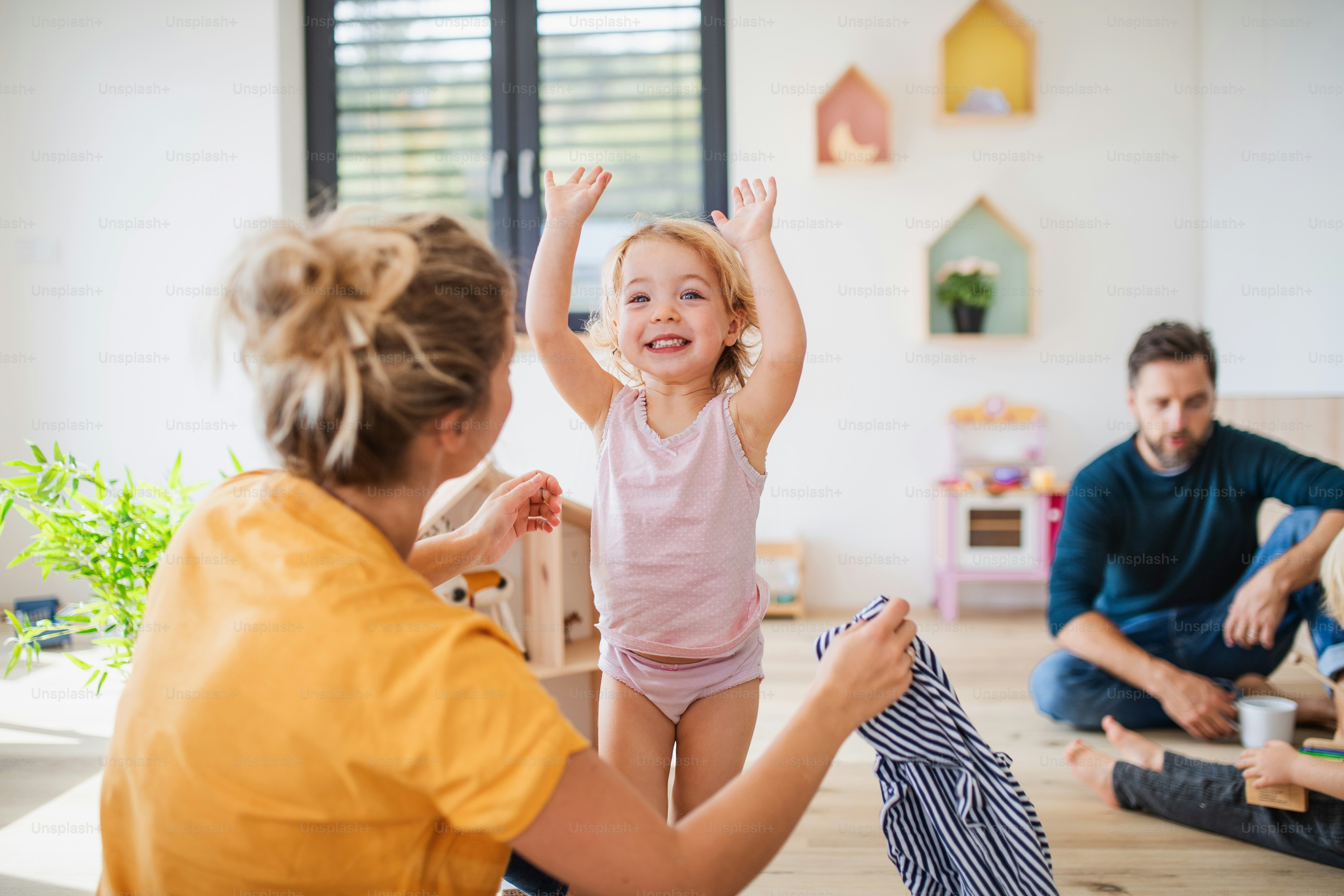 Junge Familie mit zwei kleinen Kindern drinnen im Schlafzimmer, Spaß haben.